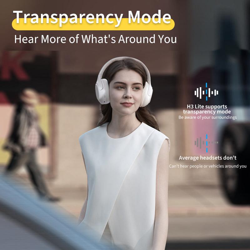 Black QCY H3 Lite headphones with transparency mode, allowing awareness of surroundings, shown on model in urban setting.