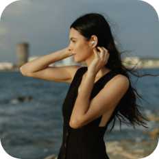 A woman walking on the beach wearing QCY HT10